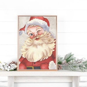 May include: A framed watercolor painting of Santa Claus with a white beard and red suit, winking and smiling. The background is a light gray.