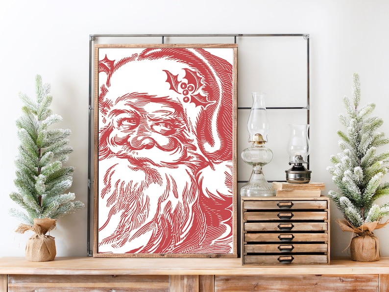 K&ouml;nnte beinhalten: Eine rote und wei&szlig;e Vintage-Illustration von Santa Claus' Gesicht. Die Illustration ist gerahmt und h&auml;ngt an einer Wand.