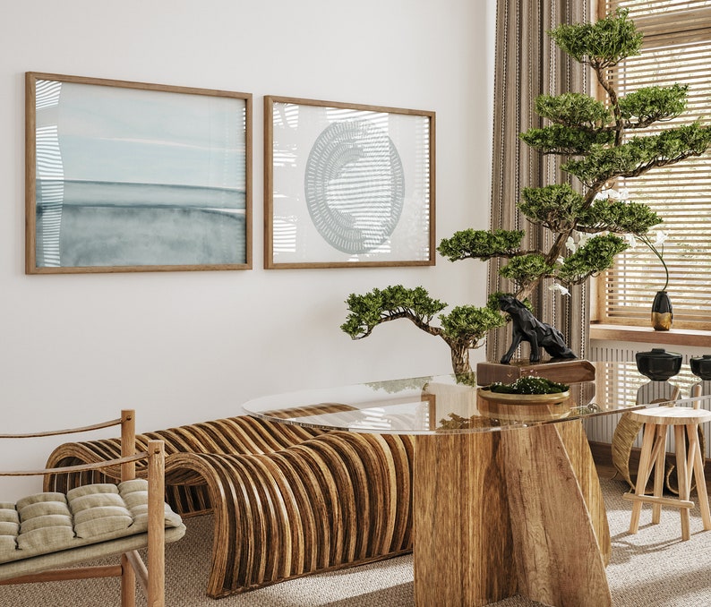 May include: A wooden table with a glass top and a unique curved wooden bench. The table is decorated with a small bonsai tree and a black sculpture. The room is decorated in a minimalist style with two framed prints on the wall.