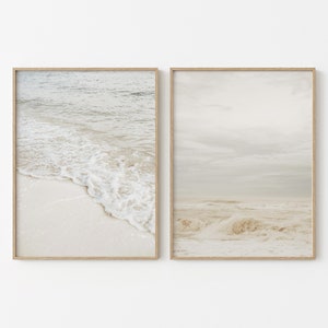 May include: Two framed prints of a beach scene. The left print shows a close-up of foamy waves crashing on the shore. The right print shows a wider view of the ocean with waves and a cloudy sky.