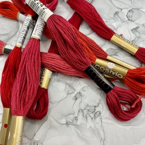 May include: Assortment of red, orange, and pink embroidery floss spools with gold labels. The labels include the text "cosmo" and "8m".