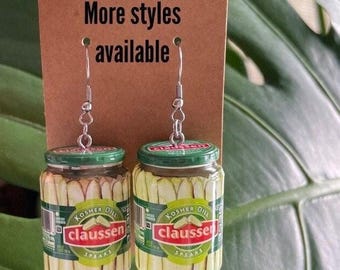 May include: A pair of dangle earrings featuring miniature glass jars with a green lid and a label that reads "Kosher Dill Claussen Spears".