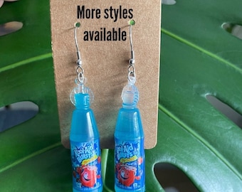 May include: A pair of blue Kool-Aid Bursts bottle earrings. The earrings are made of plastic and have silver hooks.