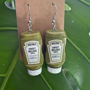 Op de afbeelding: Een paar groene Heinz Sweet Relish oorbellen. De oorbellen zijn gevormd als de iconische Heinz Sweet Relish fles. Elke oorbel heeft een zilveren haak.