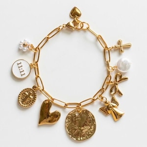 May include: Gold-toned charm bracelet featuring various charms, including a cross, heart, angel, coin, and a charm with the text "11:11". The bracelet has a heart-shaped clasp and a pearl charm.