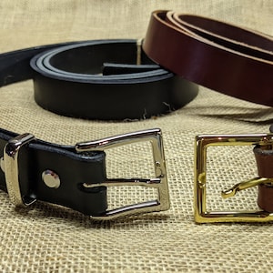 May include: Two leather belts with different buckles. One belt is brown with a gold buckle, and the other is black with a silver buckle.