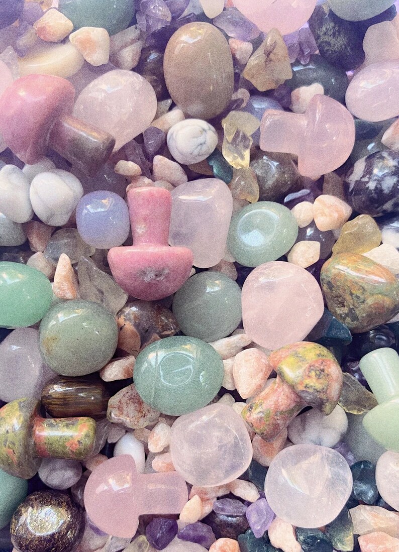 May include: A collection of various polished stones and crystals in shades of green, pink, and white. The stones are shaped like mushrooms, pebbles, and other natural forms.