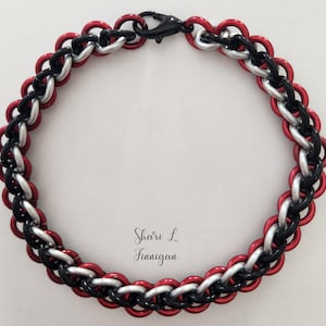 Peut inclure: Un bracelet en maille de chaîne rouge, noir et argent avec un fermoir à homard.