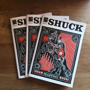 Puede incluir: Tres ejemplares de un cómic en blanco y negro titulado "Shuck: Feasting". La portada presenta un caballo negro con una capa roja y un jinete con un sombrero negro. El caballo está rodeado de llamas y el texto "Feasting" está impreso en blanco.