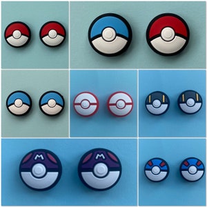 May include: Set of 10 colourful round buttons with different designs, including red, blue, and black. The buttons feature various patterns and symbols, including a Pokeball design.