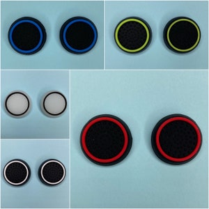 May include: Set of eight round, black, textured, silicone controller caps. The caps have a coloured ring around the edge. The colours are blue, yellow, white, and red.