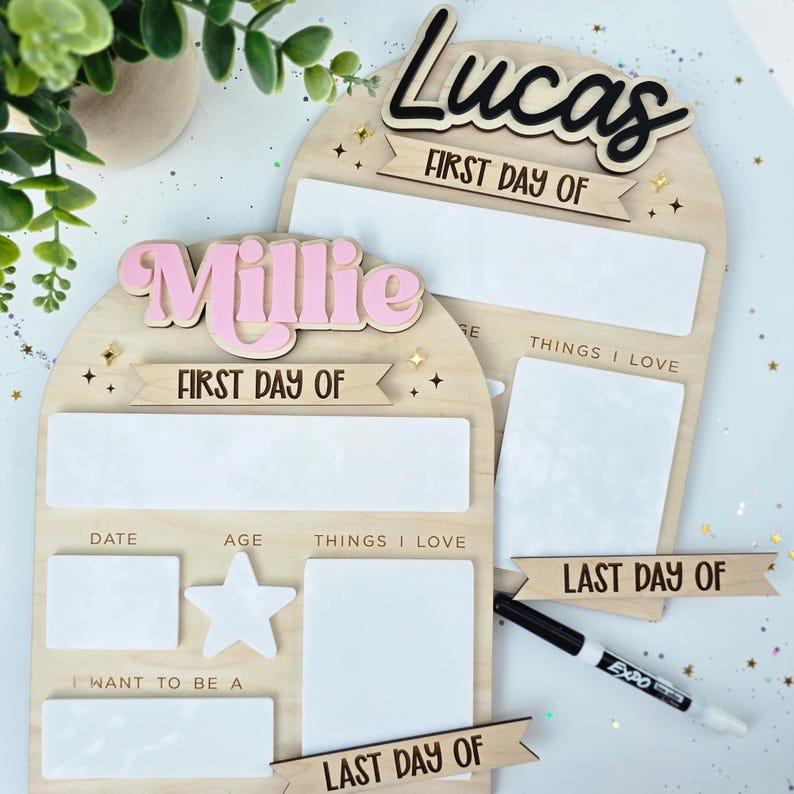 May include: Two wooden first and last day of school boards. One board has the name "Lucas" in black script, the other has "Millie" in pink. Both boards have space for date, age, and things I love.