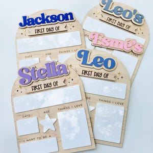 May include: Wooden first day of school signs with the names Jackson, Leo's, Esme's, Stella, and Leo in colorful 3D lettering. Each sign has space for date, age, and things they love. The signs are decorated with star and sparkle accents.