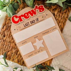 May include: Wooden sign with the text "Crew's LAST DAY OF" in red and white. The sign has spaces for "DATE", "AGE", "THINGS I LOVE", and "I WANT TO BE A". A star shape is also included. The sign is light brown.