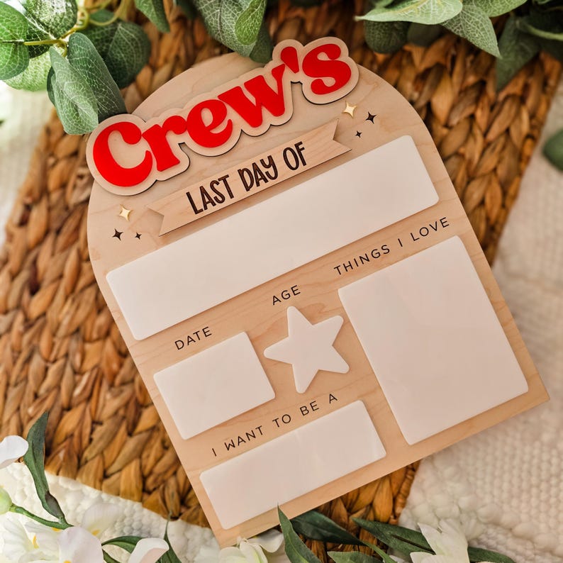 May include: Wooden sign with the text "Crew's LAST DAY OF" in red and white. The sign has spaces for "DATE", "AGE", "THINGS I LOVE", and "I WANT TO BE A". A star shape is also included. The sign is light brown.