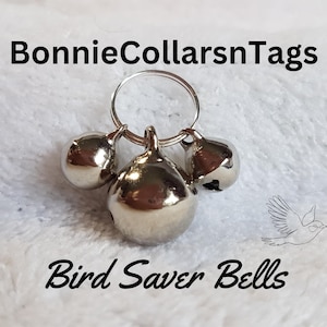 May include: Three silver bells attached to a silver ring. The bells are labeled "Bird Saver Bells".