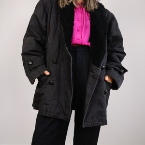 May include: A black long-sleeved jacket with a black faux fur collar. The jacket has a double-breasted closure and two pockets.
