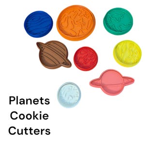 May include: A collection of colorful planet-shaped cookie cutters. The cutters are in various colors, including blue, orange, green, brown, red, yellow, light blue, and pink. The text "Planets Cookie Cutters" is displayed in black.