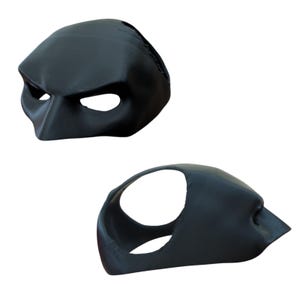 Pu&ograve; includere: Due maschere nere modellate sono mostrate su uno sfondo bianco. Le maschere hanno aperture per gli occhi e un ponte del naso. Una maschera &egrave; vista frontalmente, l'altra di lato. Le maschere sembrano essere realizzate in un materiale rigido.