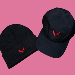 May include: Two black hats with a red V logo. One hat is a beanie and the other is a baseball cap.