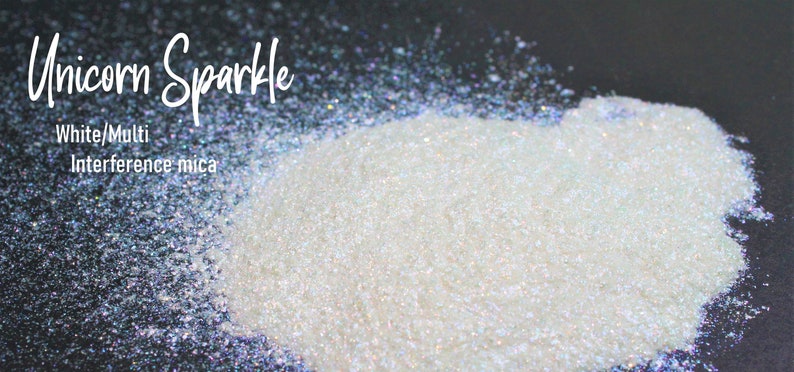 Puede incluir: Purpurina blanca e iridiscente con el texto "Unicorn Sparkle" y "White/Multi Interference mica" sobre un fondo negro.