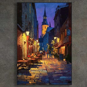 May include: An oil painting depicts a European street scene at dusk. The artwork features a cobblestone street lined with buildings, illuminated by warm streetlights. Tables and chairs are set up outside restaurants. A church steeple rises in the distance.
