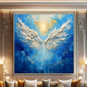 May include: Large abstract painting of white angel wings against a blue and yellow background. The artwork is displayed in a modern living room with a large sectional sofa, gold coffee table, and decorative lighting. The painting's textured brushstrokes add depth.