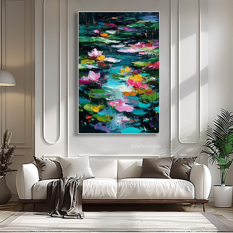 May include: An abstract painting of a pond with lily pads and flowers in shades of pink, yellow, and orange. The water reflects the colors of the flowers and the sky. The painting is displayed above a white sofa.