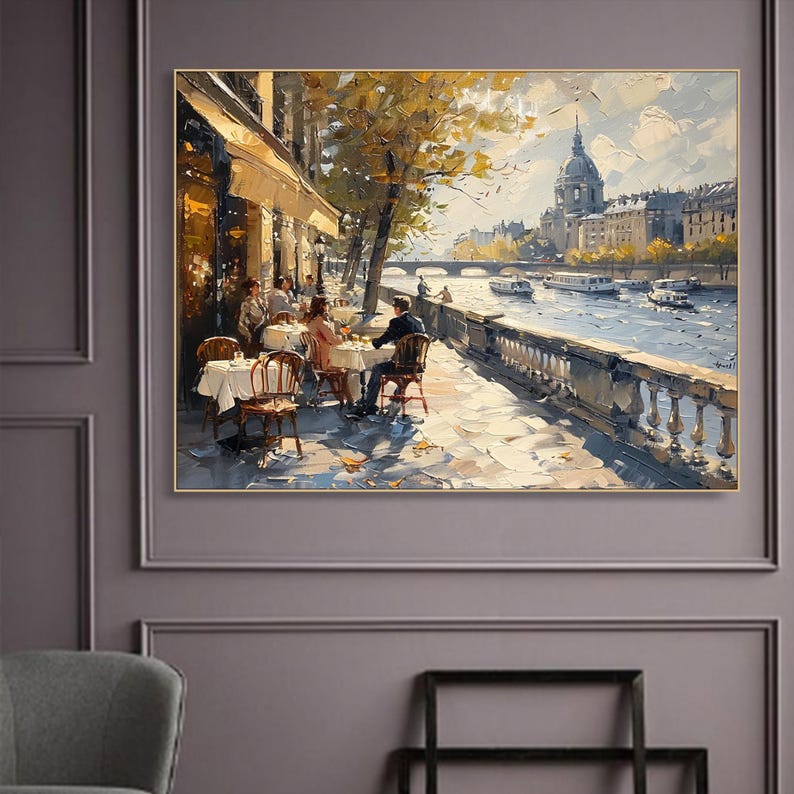 May include: A painting depicting a Parisian cafe scene with people sitting at tables on a terrace overlooking a river. The cafe is located on the banks of the Seine River, with a bridge in the distance and a church with a dome in the background. The painting is done in a realistic style with a focus on detail and light.
