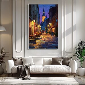 May include: An oil painting depicts a European street scene at dusk. The artwork features a cobblestone street, buildings with warm lighting, and a church steeple in the distance. The color palette includes blues, oranges, and yellows.