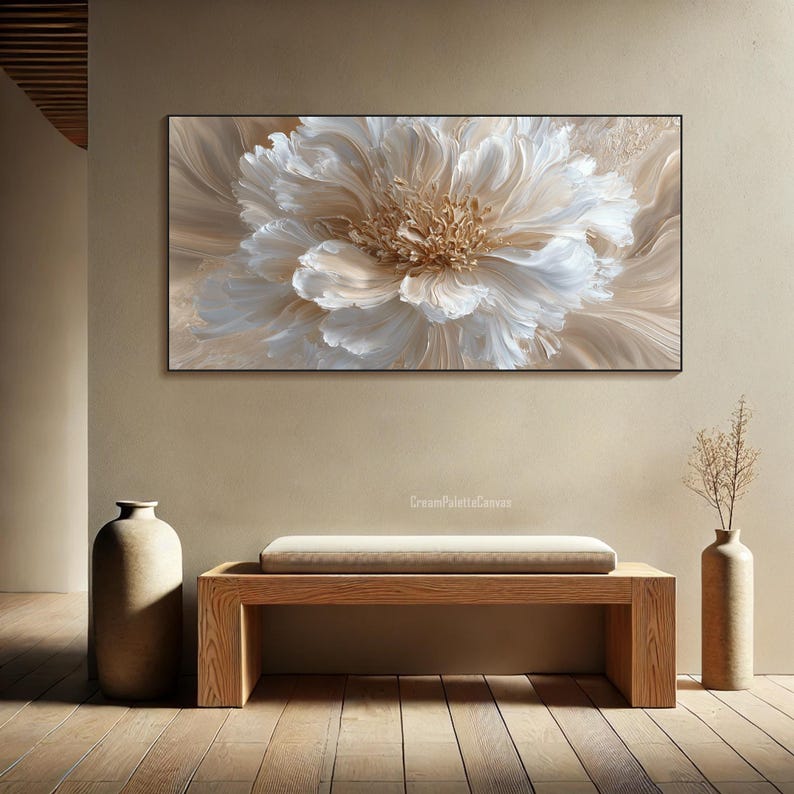 May include: A large, rectangular canvas art piece featuring a close-up of a cream-colored flower with textured petals. The artwork is framed in black and hangs above a wooden bench. The room is decorated in neutral tones.