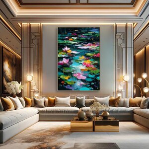 May include: Large abstract painting of a pond with lily pads and flowers in shades of pink, yellow, and green. The artwork is displayed in a modern living room with neutral-toned furniture and gold accents. The painting is the focal point of the room.