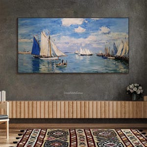May include: A framed canvas print of a seascape featuring sailboats on a blue sea under a cloudy sky. The painting has a classic, impressionistic style with visible brushstrokes. The artwork is displayed above a wooden cabinet.