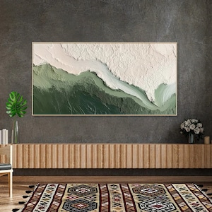May include: Abstract painting with a white and green color scheme. The painting features a textured, layered effect, creating a sense of depth and movement. The painting is framed in a thin, wooden frame.