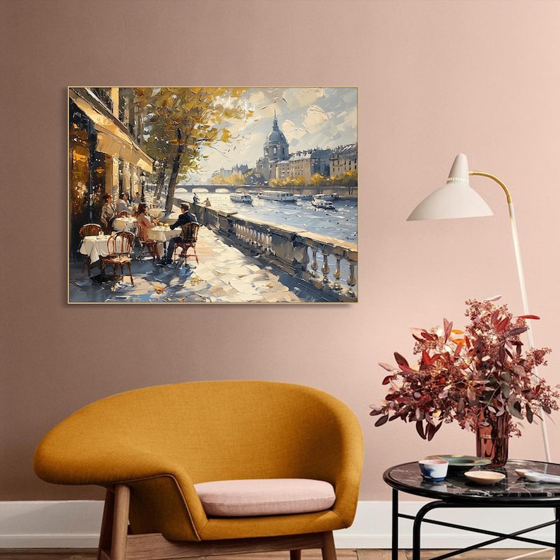 May include: A painting depicting a Parisian street scene with a cafe on the left and a river with boats in the background. The cafe has a few people sitting at tables and the river is lined with buildings. The painting is executed in a loose, impressionistic style.