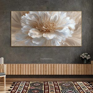 May include: A large, framed floral painting with a textured, three-dimensional effect. The artwork features a central flower in shades of white, cream, and gold, set against a neutral background. The painting is displayed above a wooden cabinet.