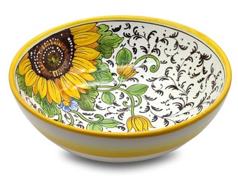 May include: A white ceramic bowl with a yellow rim and a sunflower design. The bowl is decorated with a large sunflower in the center and smaller sunflowers and leaves around the rim. The background is white with black swirls.