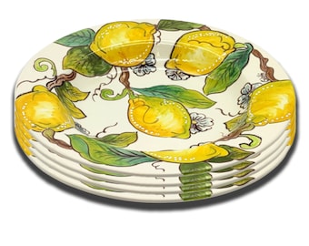 May include: A set of four white ceramic plates with a lemon tree design. The plates feature yellow lemons, green leaves, and white flowers.