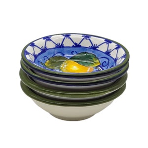 Peut inclure: Ensemble de quatre petits bols en céramique blanche avec une bordure bleue et verte. Les bols sont décorés d'un motif peint à la main de citrons et de feuilles.