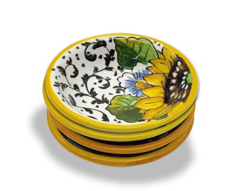 May include: A set of four small, yellow ceramic bowls with a sunflower and floral design. The bowls are stacked on top of each other.