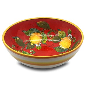 Könnte beinhalten: Eine rote Keramikschüssel mit weißem Rand und gelben Streifen. Die Schüssel ist mit einem handgemalten Design aus Zitronen und Blättern verziert.