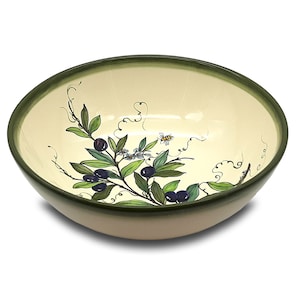 Può includere: Una ciotola da portata in ceramica con interno color crema e bordo verde scuro. La ciotola è decorata con un motivo di ramo d'ulivo dipinto a mano con foglie verdi, olive nere e una piccola ape. L'esterno è color beige chiaro.