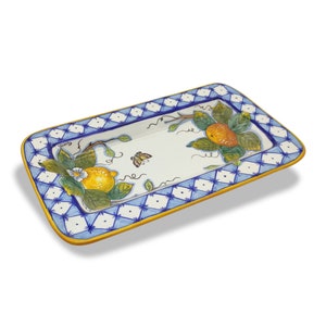 Könnte beinhalten: Eine rechteckige Servierplatte aus Keramik mit einem blauen und weißen Rautenmuster am Rand. Die Mitte zeigt ein handgemaltes Design von Zitronen an einem Weinstock mit grünen Blättern und einem Schmetterling.