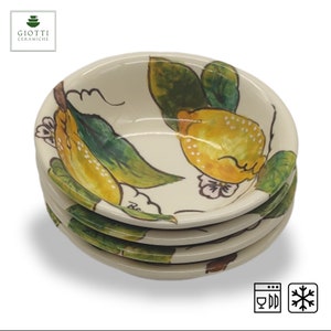 Könnte beinhalten: Set aus vier weißen Keramikschalen mit Zitronenmotiv. Die Schalen sind mit gelben Zitronen, grünen Blättern und weißen Blüten verziert. Die Schalen sind spülmaschinen- und gefrierfest.