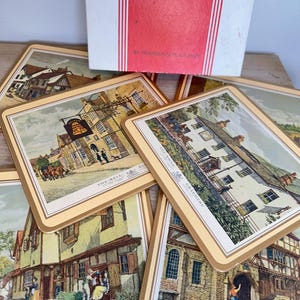 May include: A set of Pimpernel placemats featuring illustrations of historic English inns and buildings, including The Bell, The Swan, and The George. The rectangular mats have cream borders and are presented with their original white and red box.