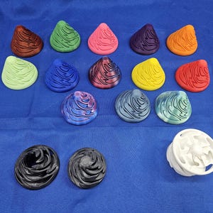 May include: A collection of 15 colorful, swirling, cone-shaped objects. The objects are made of a smooth, hard material and have a variety of colors, including red, blue, green, yellow, and purple. There are also two black objects that are similar in shape but have a more textured surface.
