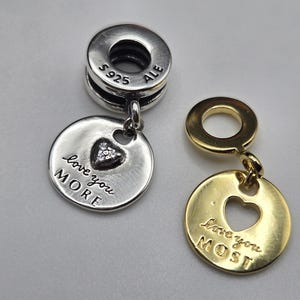 May include: Two silver and gold charm bracelets with heart-shaped pendants. The silver charm says "love you more" and the gold charm says "love you most".