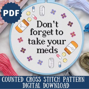 May include: A counted cross stitch pattern for a digital download. The pattern features a blue background with white text that reads "Don't forget to take your meds". The pattern also includes small images of pills and flowers.