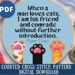 May include: A blue and white counted cross stitch pattern featuring a quote by Mark Twain: "When a man loves cats, I am his friend and comrade without further introduction." The pattern includes three paw prints, one black, one orange, and one white.