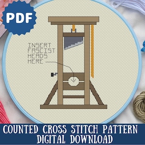 May include: A counted cross stitch pattern digital download featuring a guillotine design. The design includes the text "INSERT FASCIST HEADS HERE". The image is set in a blue embroidery hoop with various colored threads.
